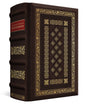 A classic hardcover book with a dark brown leather-like cover, ornate gold foil detailing, and a red title block on the spine, shown on a clean white background.