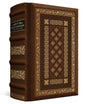 A luxury leather-bound Bible shown at a three-quarter angle on a white background. The cover is dark brown leather with ornate gold foil detailing, and a black title label is visible on the spine.